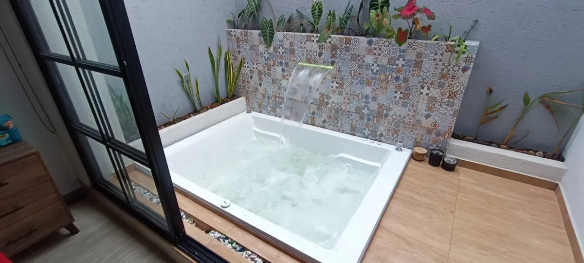 Jacuzzi empotrado con cascada sobre un muro de baldosa decorativa